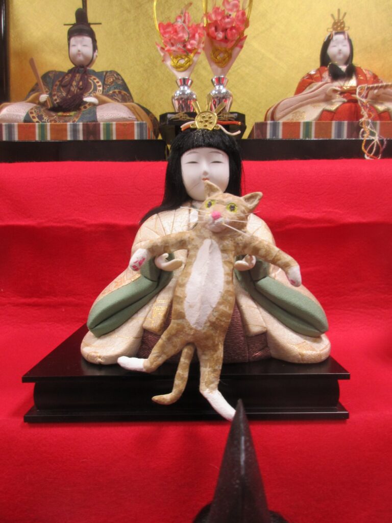 お雛様に抱っこされる猫
